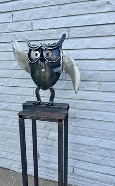 an owl statue on top of a metal stand