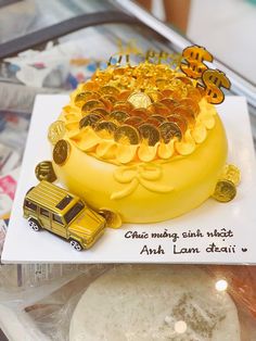 a yellow cake with gold coins on top and a school bus in the back ground