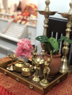 there is a tray that has some brass items on it and flowers in the vases