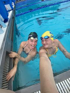 two people are swimming in a pool with their hands on the side of the pool