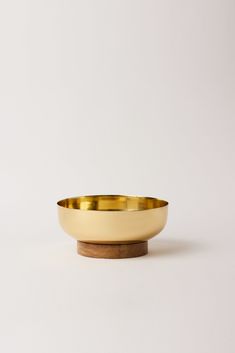 a gold bowl sitting on top of a wooden stand