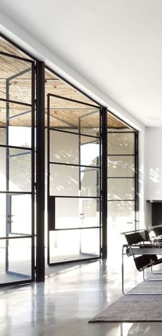 an empty living room with black furniture and large glass doors that open up to the outside