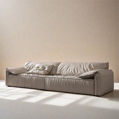 a white couch sitting on top of a hard wood floor next to a wall and window