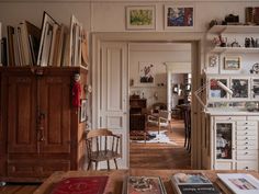 a living room filled with lots of books on top of a hard wood floored floor