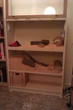 a book shelf filled with lots of books and other items in a room next to a wall