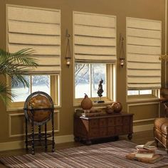 a living room filled with furniture and windows covered in roman blind shades on top of them