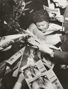 an old black and white photo of a woman surrounded by magazine pages, reading magazines