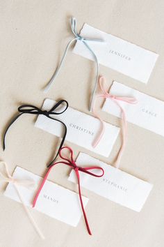 four different colored ribbons tied to each other on top of white cards with name tags