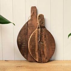 a wooden cutting board sitting on top of a table next to a potted plant