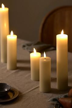 five lit candles sitting on top of a table next to a plate and spoons