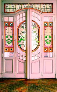 an open pink door with stained glass on the top and bottom panels, in front of a wooden floor