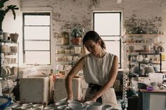 a woman standing in front of stacks of white plates and bowls on a counter top