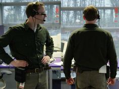 two men wearing headsets are standing in an office