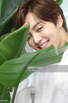 a young man is smiling and leaning on a plant