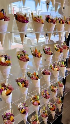 a display case filled with lots of different types of flowers and fruit in paper cones