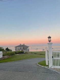 a white picket fence next to a house near the ocean