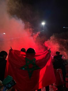 some people are holding a red and green flag in front of the camera at night