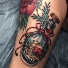 a woman's thigh with a jar filled with flowers and a skull in it