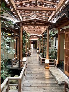 the inside of a building with wooden benches and plants on either side of the walkway