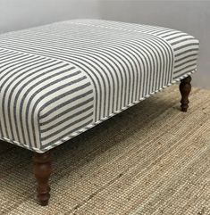 a striped ottoman sitting on top of a rug