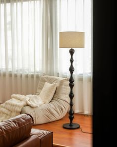 a living room scene with focus on the floor lamp and couch in the foreground