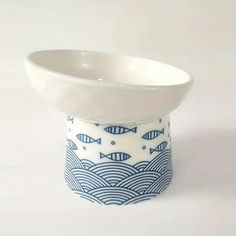 a white and blue bowl with fish on the bottom is sitting in front of a white background