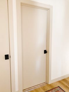 an empty room with two white doors and a rug on the floor next to it