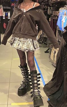 a mannequin dressed in black and white clothing with spikes on her legs, standing next to a mirror