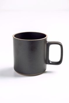 a black and gold colored coffee mug on a white background with the lid off to the side