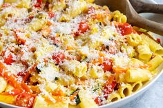 a bowl filled with pasta and cheese on top of a white tablecloth next to a wooden spoon