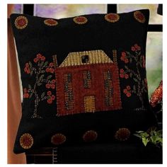 a black pillow with a red house on the front and yellow flowers on the back