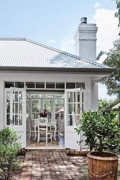 a white house with glass doors and brick patio