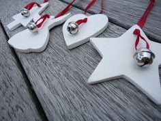 three wooden ornaments with bells on them are hanging from red ribbon and wood planks