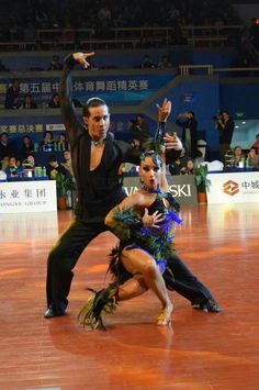 two professional dancers performing on the floor in front of an audience with their arms outstretched