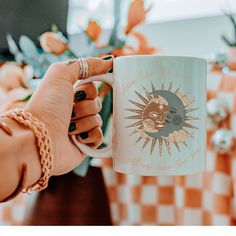 a person holding a coffee mug with the sun and moon on it