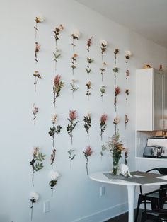 flowers are arranged on the wall above a table in front of a kitchen counter top