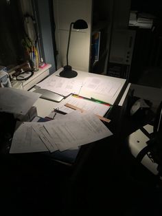 some papers are sitting on a desk with a lamp next to it and a computer mouse