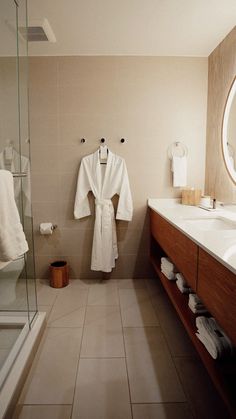 a bathrobe in the corner of a bathroom next to a sink and shower