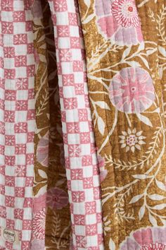 the fabric is pink and brown with flowers on it, as well as checkered material