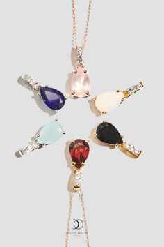 six different colored stones are arranged in the shape of a bird on a gold chain