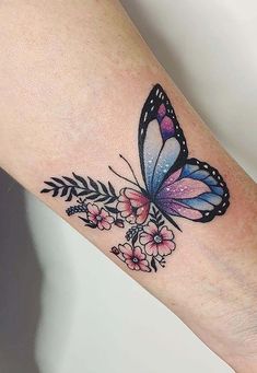 a colorful butterfly tattoo on the left forearm and right arm, with flowers around it