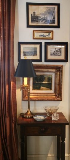 a table with a lamp and pictures on the wall