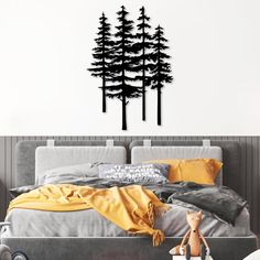 a bed room with a neatly made bed and a wall decal that has trees on it