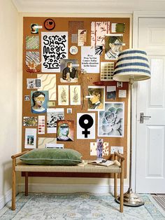 a room with a wall covered in pictures and magnets on the wall next to a lamp