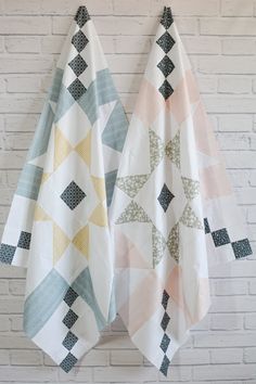 two towels hanging on a brick wall next to each other, one with an abstract design