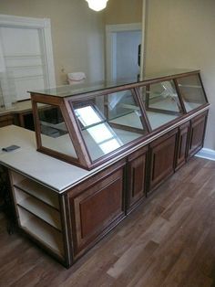 an empty room with wooden flooring and glass display cases on the wall, along with hard wood floors