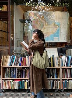 a woman standing in front of a book store talking on her cell phone