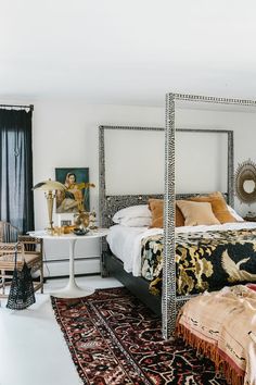 a bedroom with a four poster bed and rugs on the floor in front of it