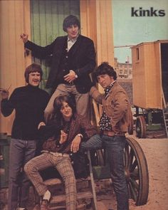 the kinks are posing for a photo in front of a yellow building with green doors