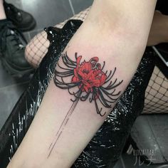 a woman's arm with a spider and red flower tattoo on her left forearm